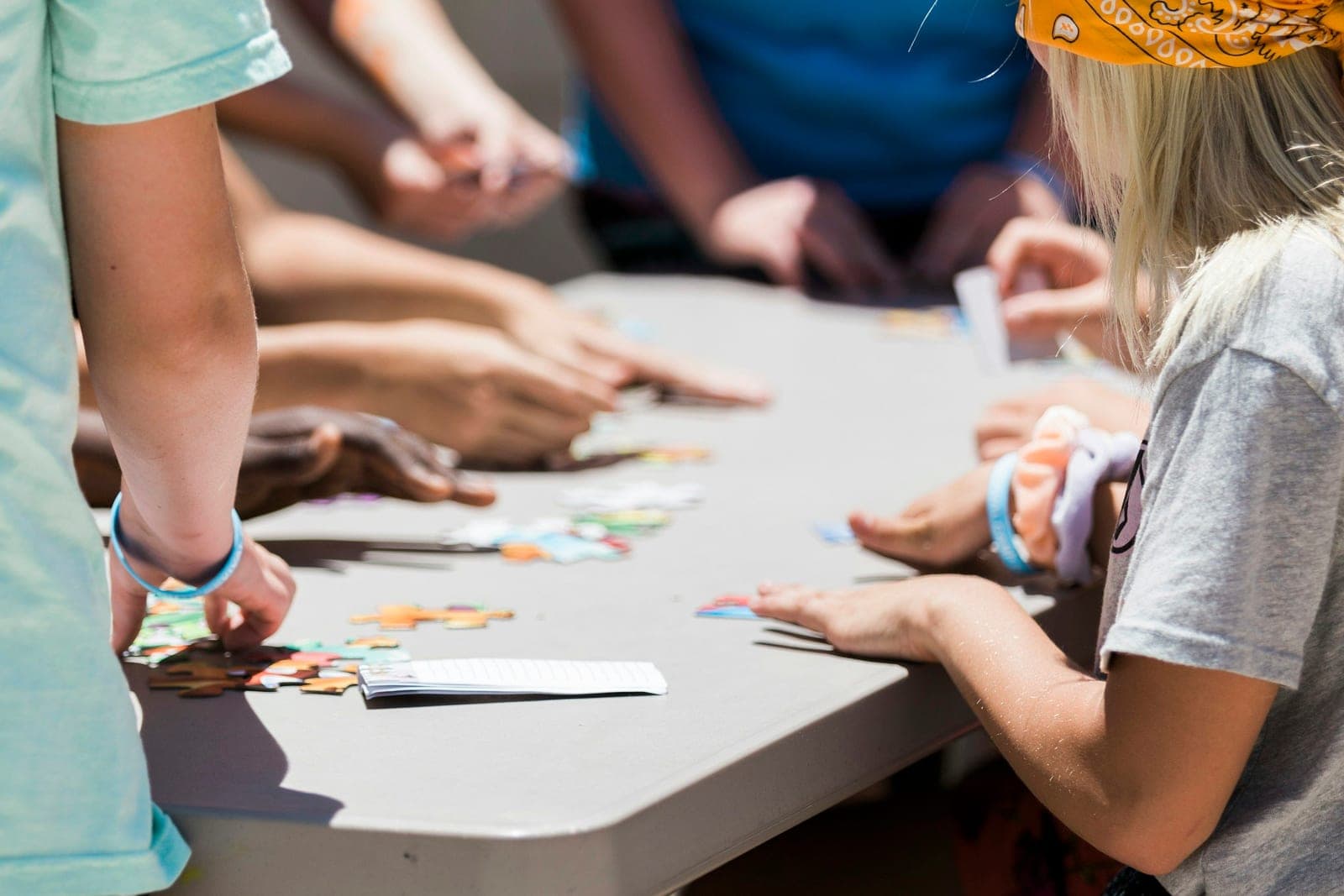 Pre-teens gathered around a table, working together to piece together a colorful jigsaw puzzle.